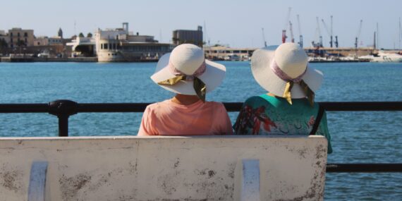 Two women is sitting on a bench by the seaside. Harbour